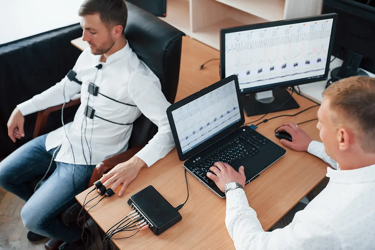 Polygraph examiner administering a lie detector test while monitoring results on a computer screen