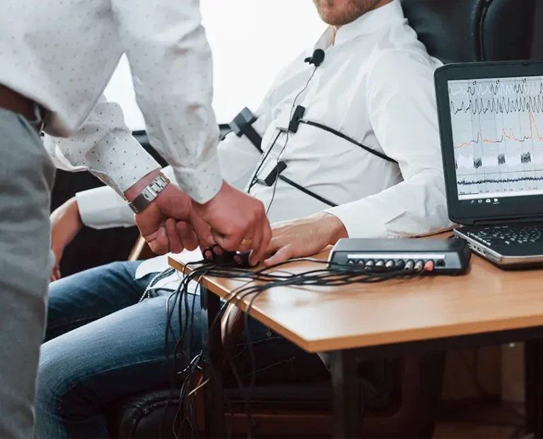 Polygraph examiner attaching sensors to a client’s hand during the pre-test interview stage of polygraph testing services